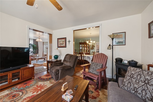 living room featuring ceiling fan with notable chandelier and hardwood / wood-style floors