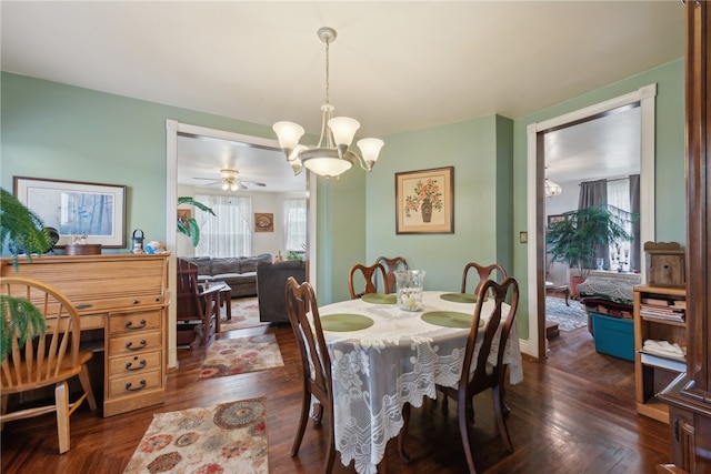 dining room with dark hardwood / wood-style flooring and ceiling fan with notable chandelier