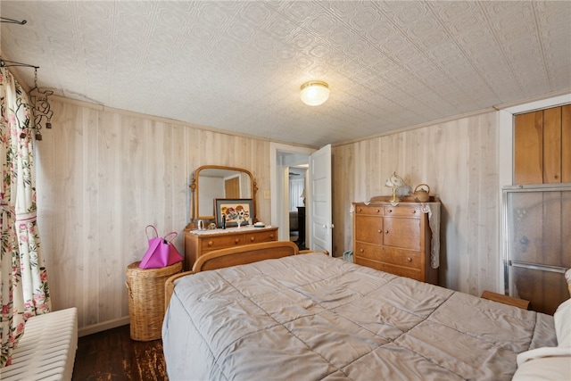 bedroom with a textured ceiling, wooden walls, and hardwood / wood-style floors