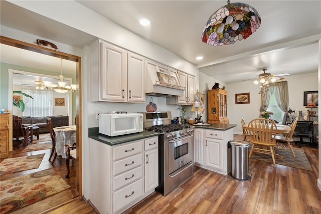 kitchen with custom range hood, ceiling fan with notable chandelier, hardwood / wood-style flooring, high end range, and white cabinetry