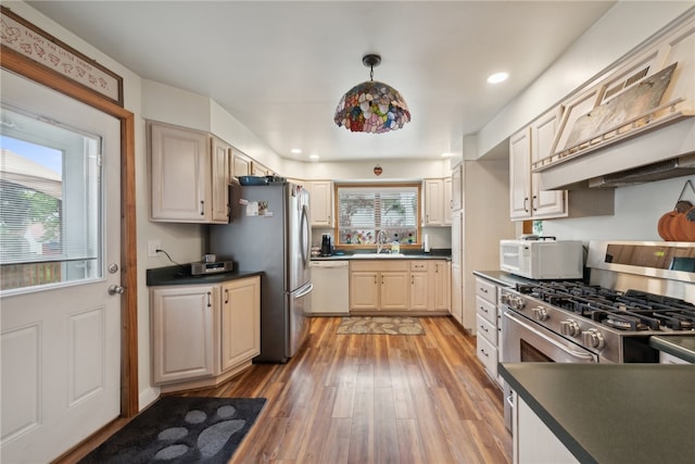 kitchen featuring decorative light fixtures, light hardwood / wood-style flooring, stainless steel appliances, custom exhaust hood, and sink