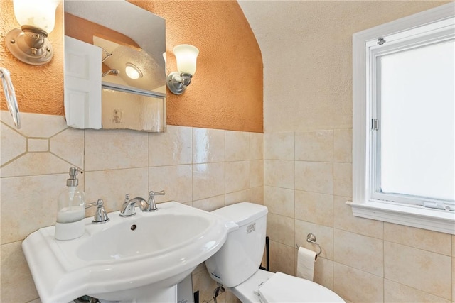 bathroom featuring sink, tile walls, and toilet