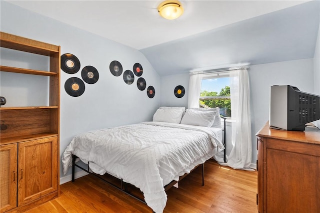 bedroom featuring light hardwood / wood-style flooring and vaulted ceiling