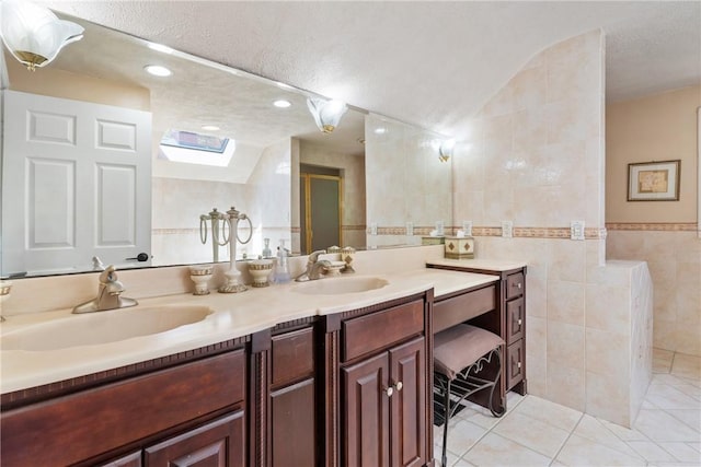 bathroom featuring tile patterned floors, vanity, lofted ceiling with skylight, and tile walls