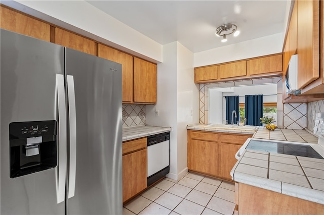 kitchen with dishwasher, sink, stainless steel fridge, and tasteful backsplash