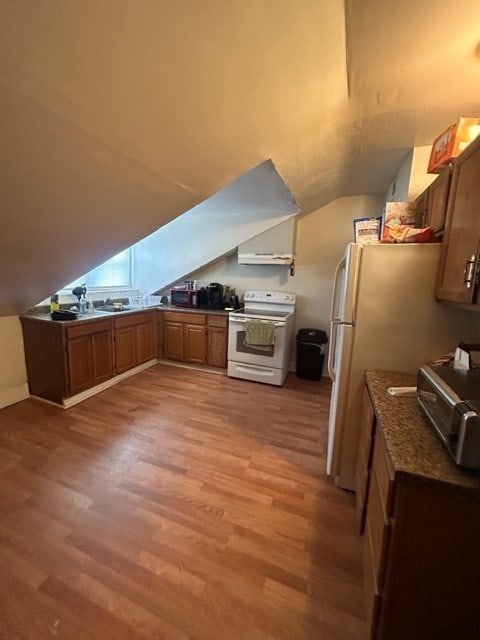 kitchen with white appliances, hardwood / wood-style flooring, and vaulted ceiling