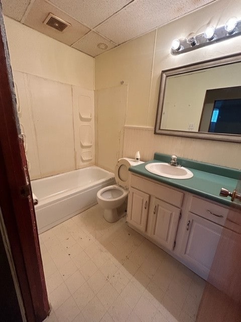 full bathroom featuring washtub / shower combination, toilet, tile floors, a drop ceiling, and vanity