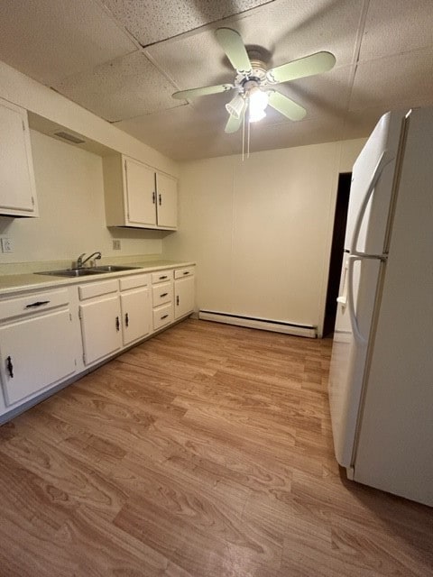 kitchen with ceiling fan, light hardwood / wood-style flooring, white fridge, a baseboard radiator, and white cabinetry