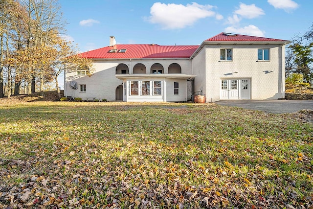 rear view of house featuring french doors and a lawn