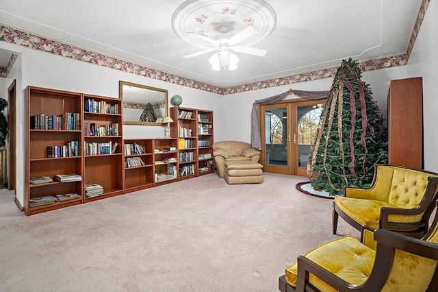 living area with ceiling fan, carpet floors, a textured ceiling, and french doors