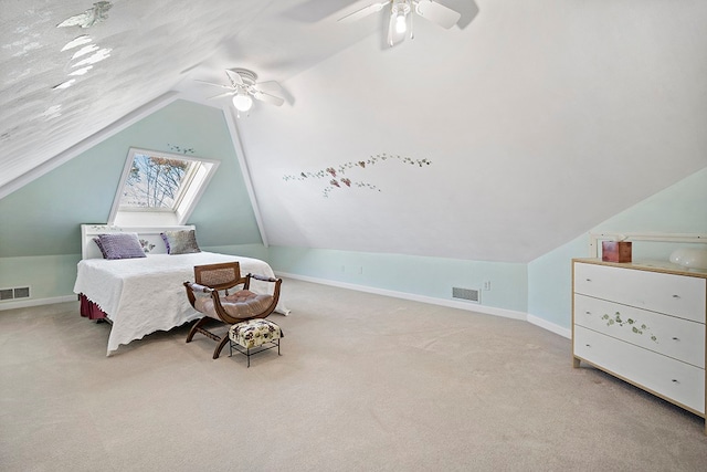 bedroom with ceiling fan, vaulted ceiling with skylight, and light colored carpet