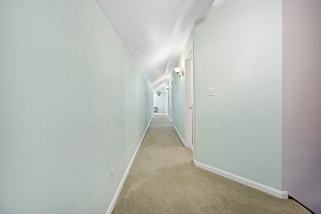 hallway featuring vaulted ceiling and light carpet