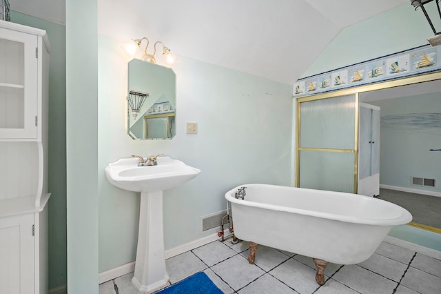 bathroom with tile flooring, lofted ceiling, and a bath to relax in