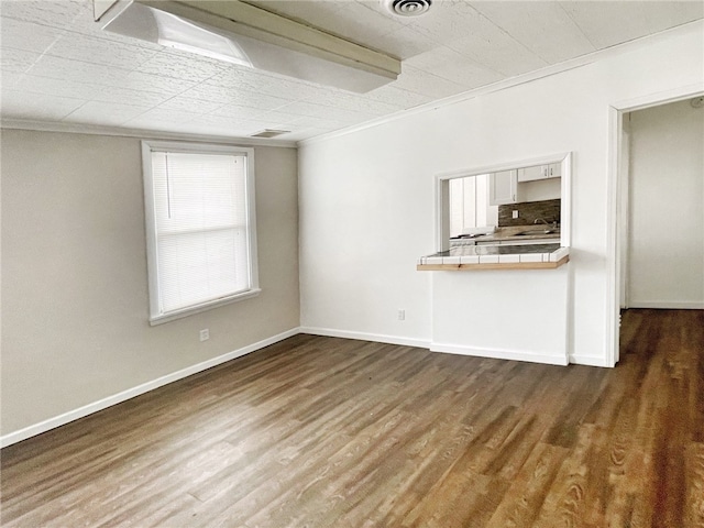 unfurnished living room with sink, ornamental molding, and hardwood / wood-style flooring