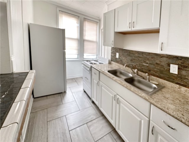 kitchen with white appliances, a healthy amount of sunlight, white cabinets, and tasteful backsplash