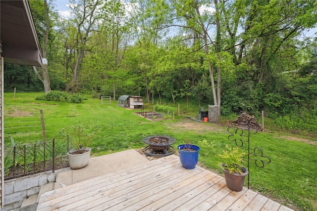 wooden deck featuring a yard and a fire pit