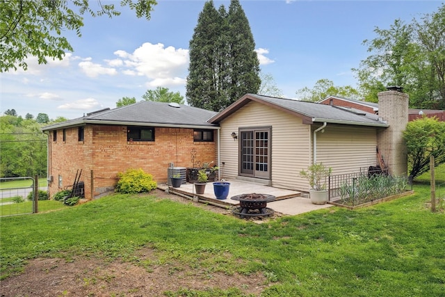 rear view of property with a yard, a fire pit, and a patio