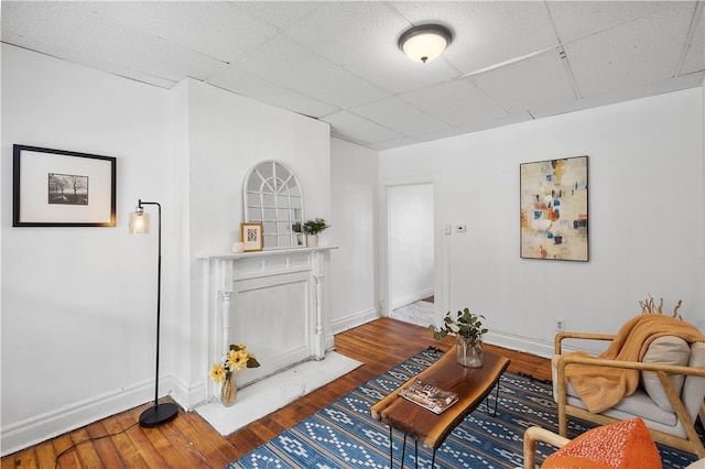 living room with dark hardwood / wood-style floors, a fireplace, and a drop ceiling