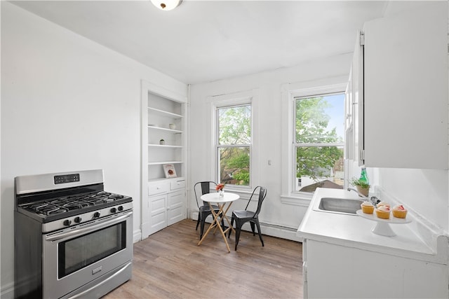 kitchen with light hardwood / wood-style flooring, stainless steel range with gas cooktop, a baseboard heating unit, sink, and white cabinets