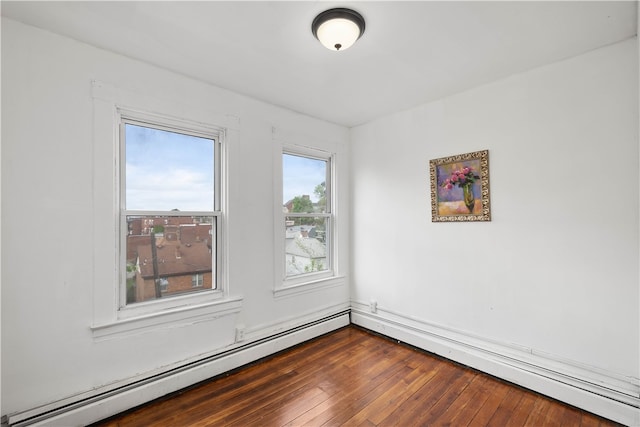 empty room with dark hardwood / wood-style floors and a baseboard radiator