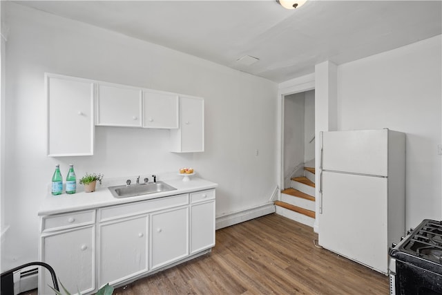 kitchen with white refrigerator, a baseboard radiator, gas range, white cabinetry, and wood-type flooring