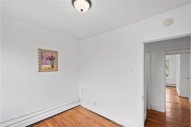 unfurnished room featuring baseboard heating and hardwood / wood-style flooring