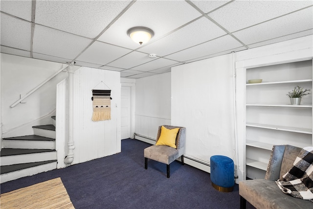 sitting room with a paneled ceiling, a baseboard radiator, and dark colored carpet