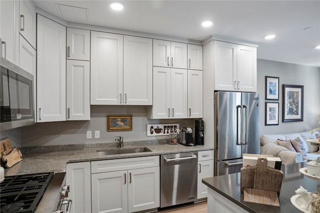 kitchen with sink, white cabinets, dark stone counters, and high end appliances