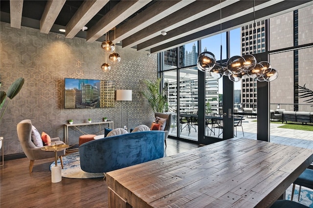 dining space featuring beamed ceiling, a wall of windows, wood-type flooring, and a towering ceiling