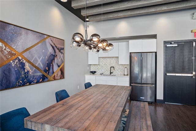 dining space featuring beamed ceiling, dark hardwood / wood-style flooring, sink, and a chandelier