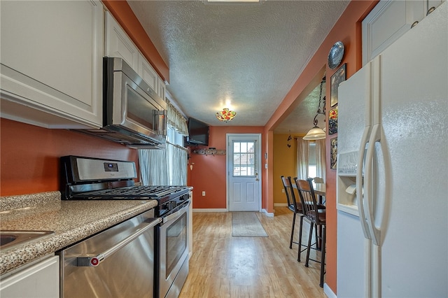 kitchen with appliances with stainless steel finishes, light hardwood / wood-style floors, and a textured ceiling