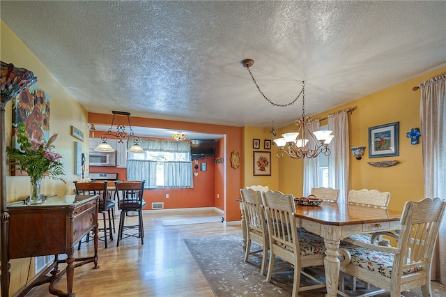 dining room with a notable chandelier, a textured ceiling, and wood-type flooring