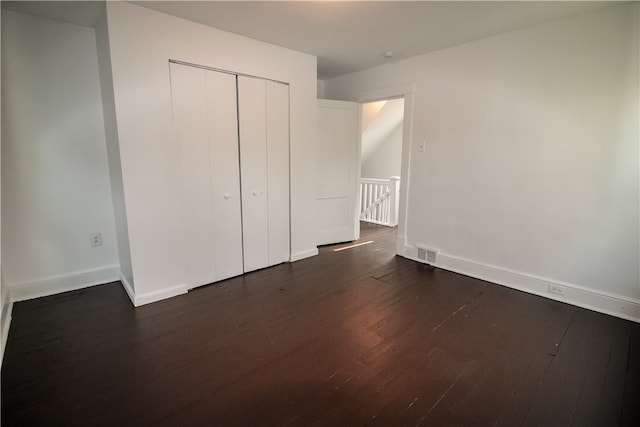 unfurnished bedroom with dark hardwood / wood-style floors and a closet