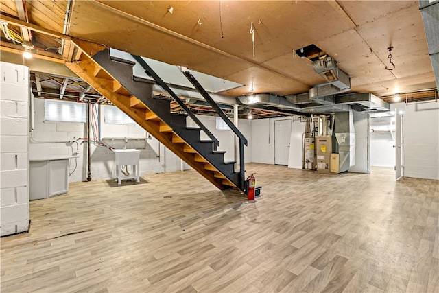 basement with heating utilities, light hardwood / wood-style flooring, and gas water heater