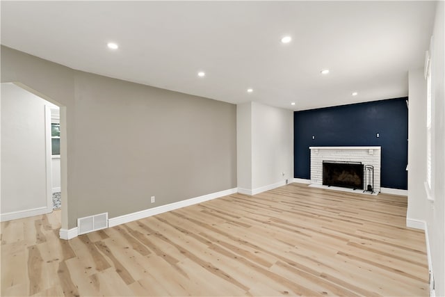 unfurnished living room with a fireplace and light wood-type flooring