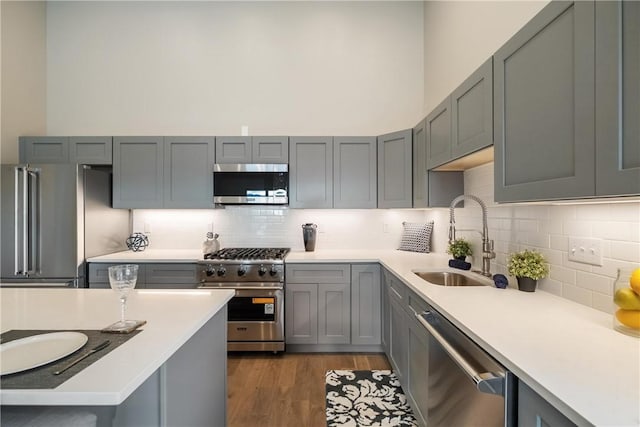 kitchen featuring appliances with stainless steel finishes, sink, gray cabinetry, and decorative backsplash