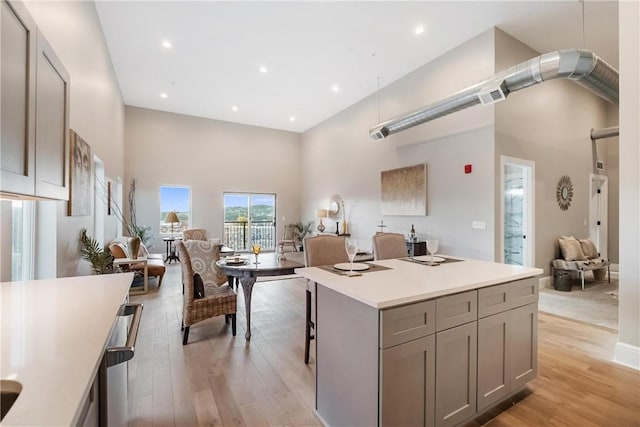 kitchen featuring gray cabinetry, light hardwood / wood-style floors, a high ceiling, and a kitchen island