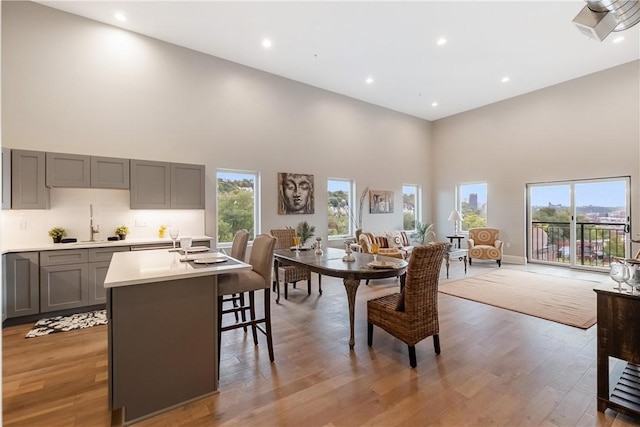 dining room featuring sink, light wood-type flooring, plenty of natural light, and a high ceiling