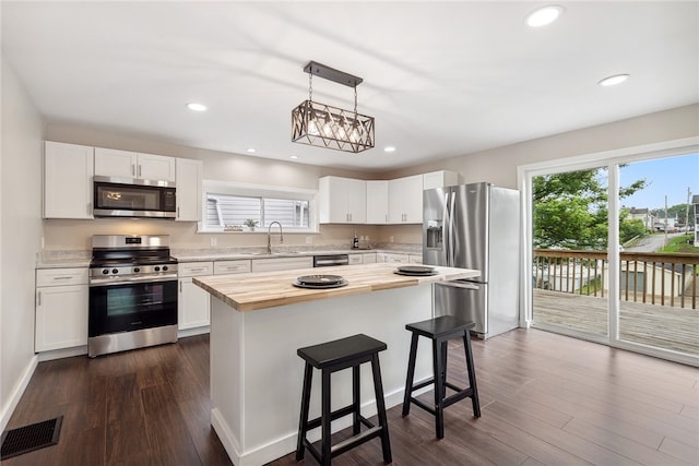 kitchen featuring a center island, dark wood-type flooring, white cabinets, and appliances with stainless steel finishes