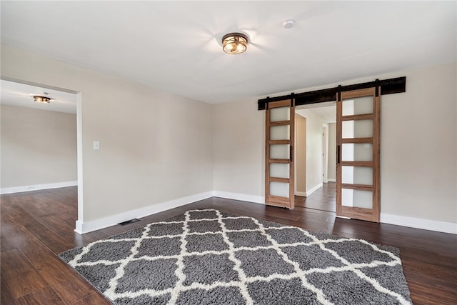 spare room featuring a barn door and dark hardwood / wood-style floors