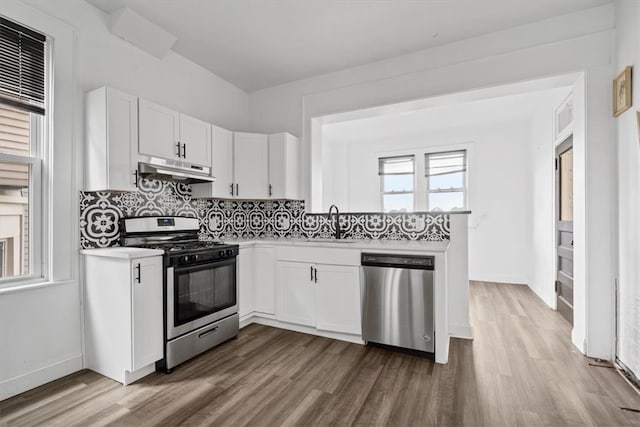 kitchen with backsplash, appliances with stainless steel finishes, and hardwood / wood-style floors