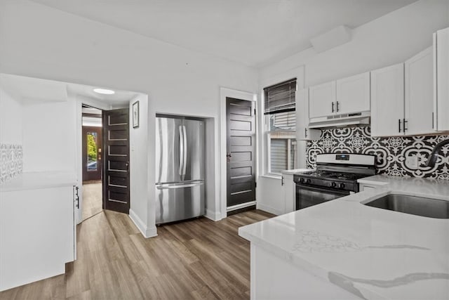 kitchen featuring stainless steel appliances, light hardwood / wood-style floors, white cabinets, and tasteful backsplash