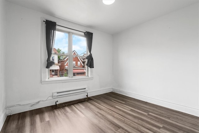 unfurnished room featuring a baseboard heating unit and wood-type flooring