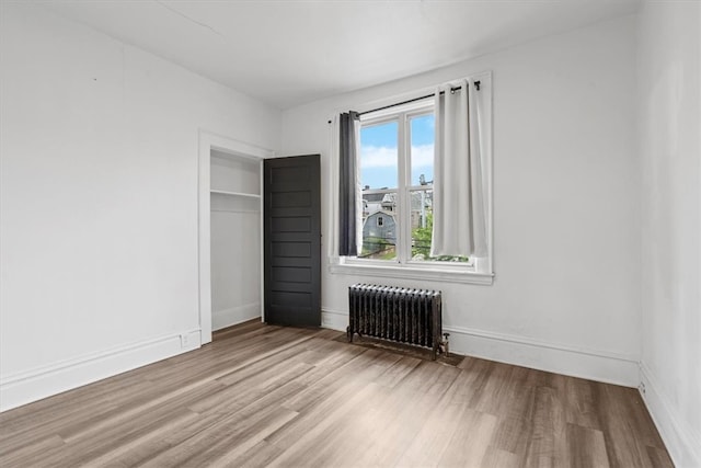 interior space with multiple windows, hardwood / wood-style floors, a closet, and radiator heating unit