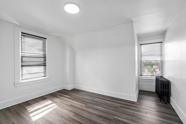 unfurnished room featuring dark hardwood / wood-style flooring and radiator heating unit