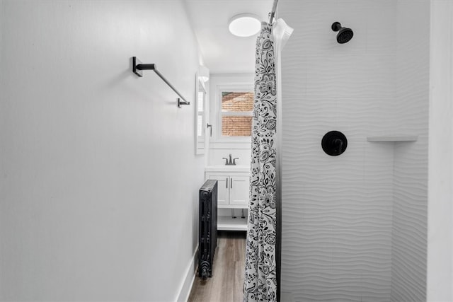 bathroom featuring a tile shower, sink, and wood-type flooring