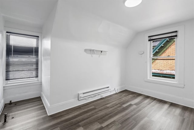 additional living space featuring dark wood-type flooring, a baseboard heating unit, and vaulted ceiling