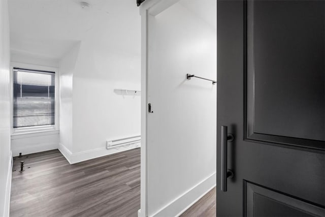 hallway with dark wood-type flooring and a baseboard heating unit