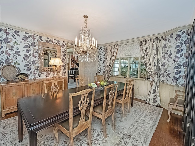 dining area with ornamental molding, hardwood / wood-style floors, and an inviting chandelier