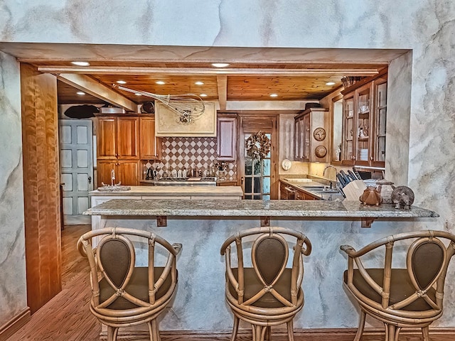 bar featuring stone counters, sink, and light hardwood / wood-style floors